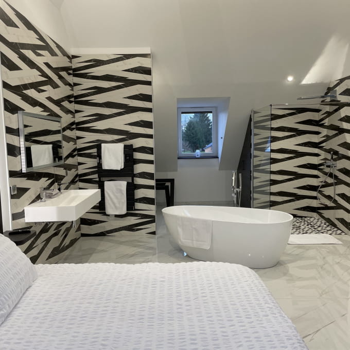 Chambre bien-être contemporaine avec baignoire design et lit à deux en amoureux