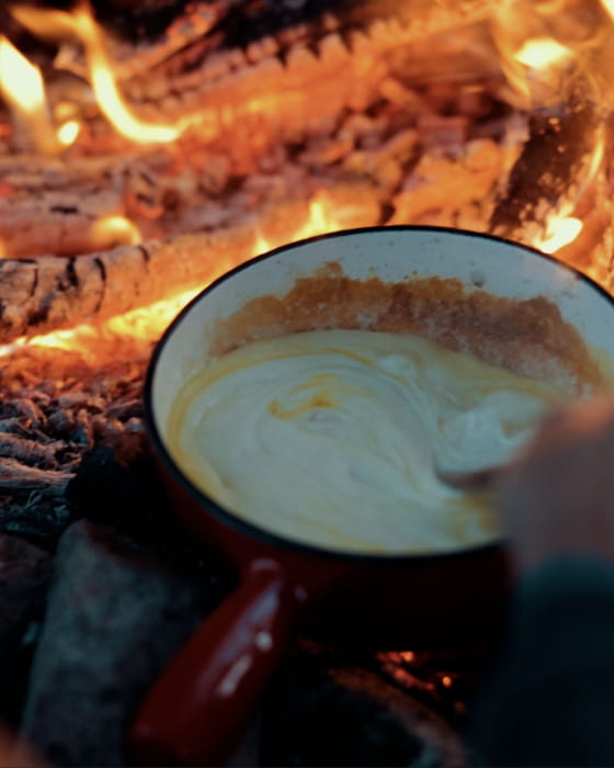 Préparation d’une fondue au feu de camp en bivouac dans les Vosges du Sud